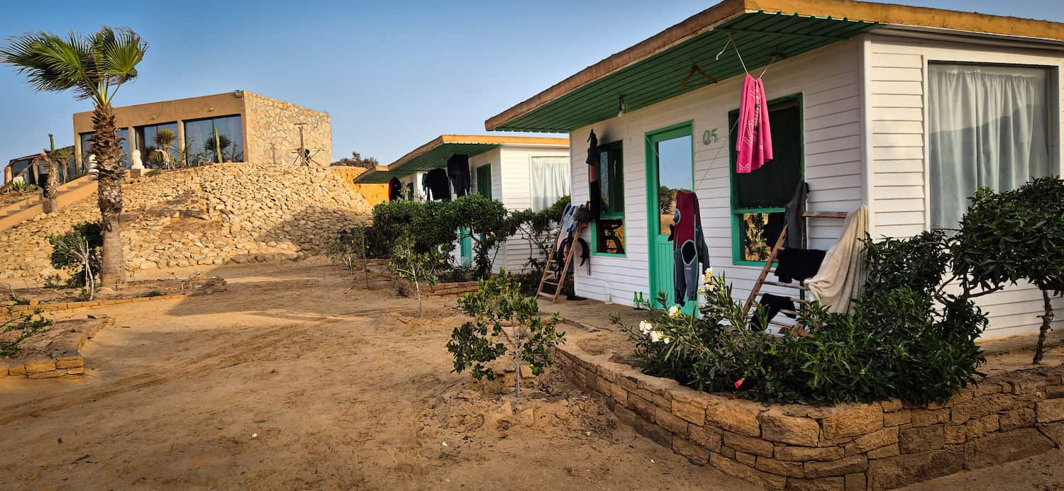 De hvide og grønne udendørs træhytter og bungalows på Auberge des Nomades du Sahara.