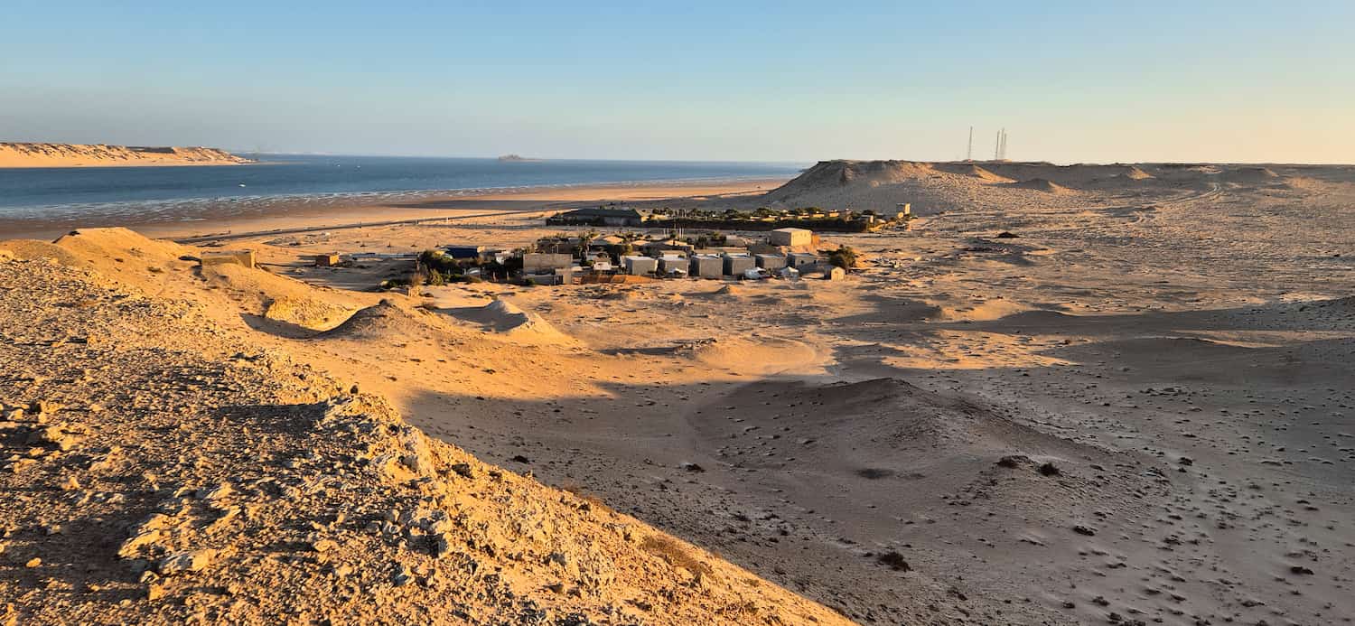 Udsigt over Auberge des Nomades du Saharafra den tilstødende bakke med lagunen og sandklitterne i baggrunden under det varme eftermiddagslys