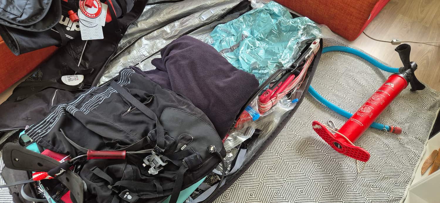 Fully packed kiteboarding travel bag with kites, control bar, kite pump, and a impact vest arranged tightly
